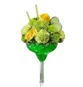 a glass with a yellow and green flower arrangement